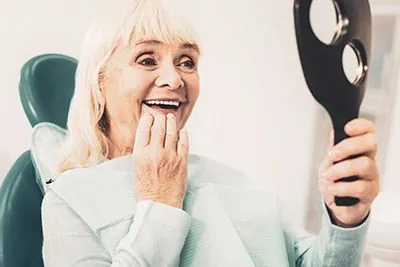woman loving the look of her smile after getting dental implants at Smiles on Elston